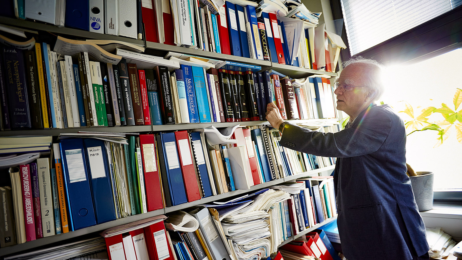 Professor Philippe Grandjean står og kigger på en bogreal.